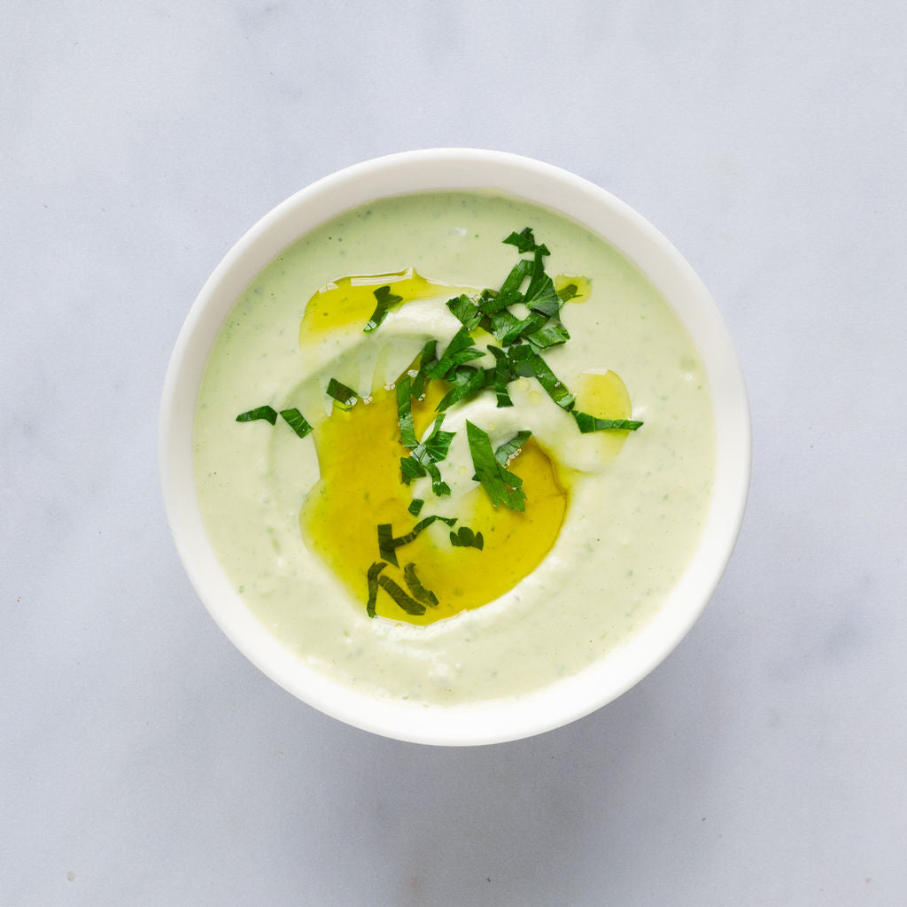 mamoosh green tahini dip in a bowl with herbs