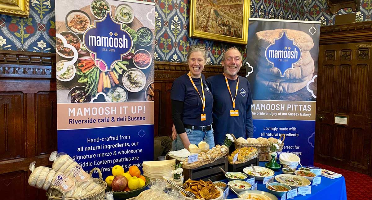 Mamoosh stand at the Houses of Parliament with Einat and Gary standing beside their table