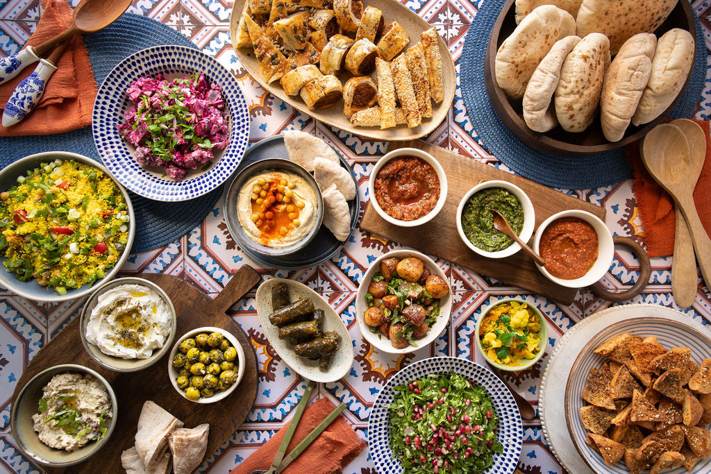 Mamoosh buffet spread pitta bread, middle eastern dips, salads, pitta chips on a tiled table top